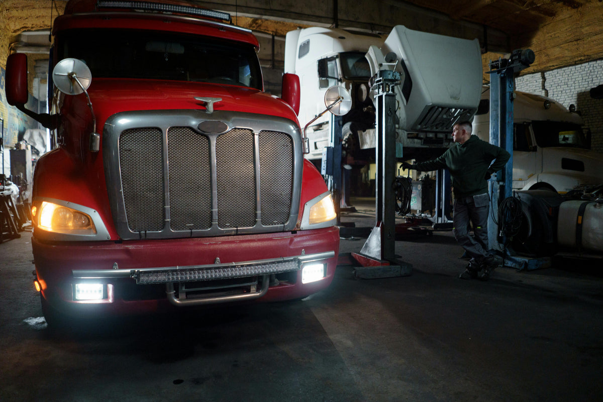 Mechanic working on a heavy-duty truck on a lift in an industrial garage