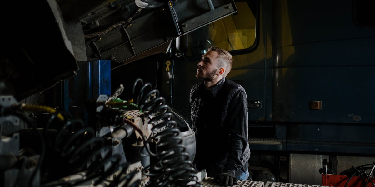 Truck mechanic carefully examining a heavy-duty engine in a garage workshop