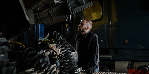 Truck mechanic carefully examining a heavy-duty engine in a garage workshop